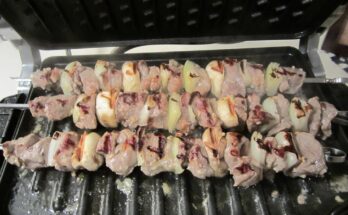 Three souvlaki skewers on a black grill