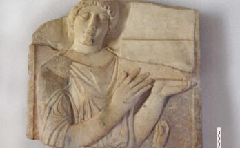 A section of a marble tombstone featuring a relief of a woman holding a jewel case.