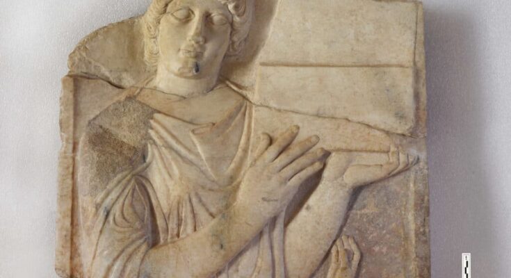 A section of a marble tombstone featuring a relief of a woman holding a jewel case.