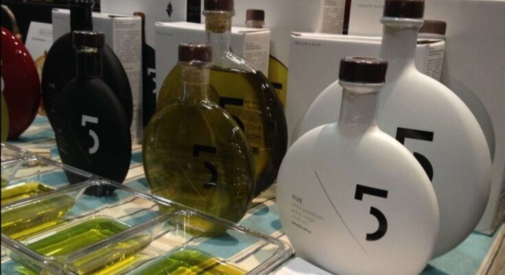 A selection of Greek olive oil bottles displayed on a wooden surface, showcasing various brands and sizes.